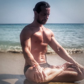 David Keens seated in lotus on a beach