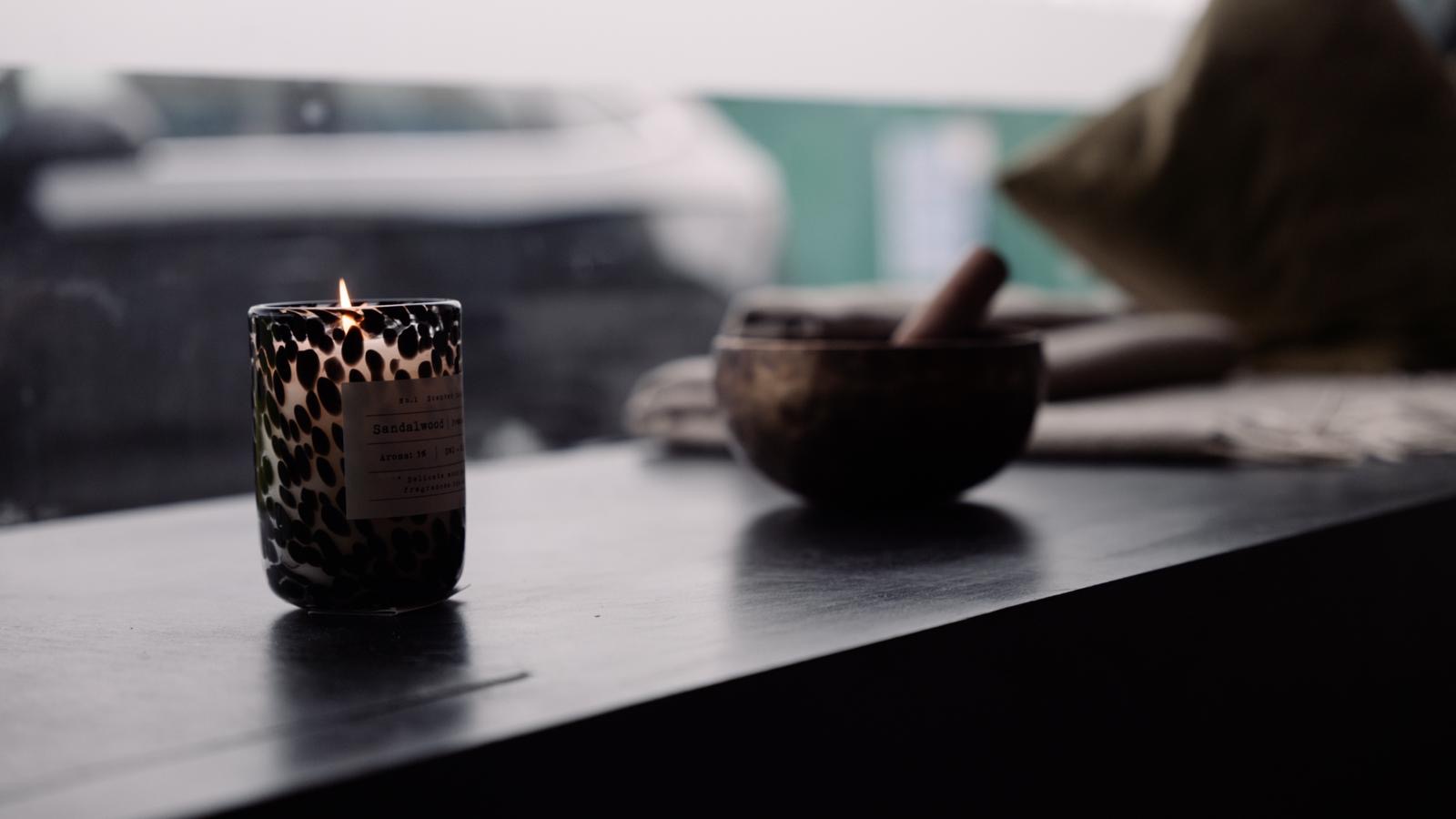 A lit candle and a singing bowl on the window seat