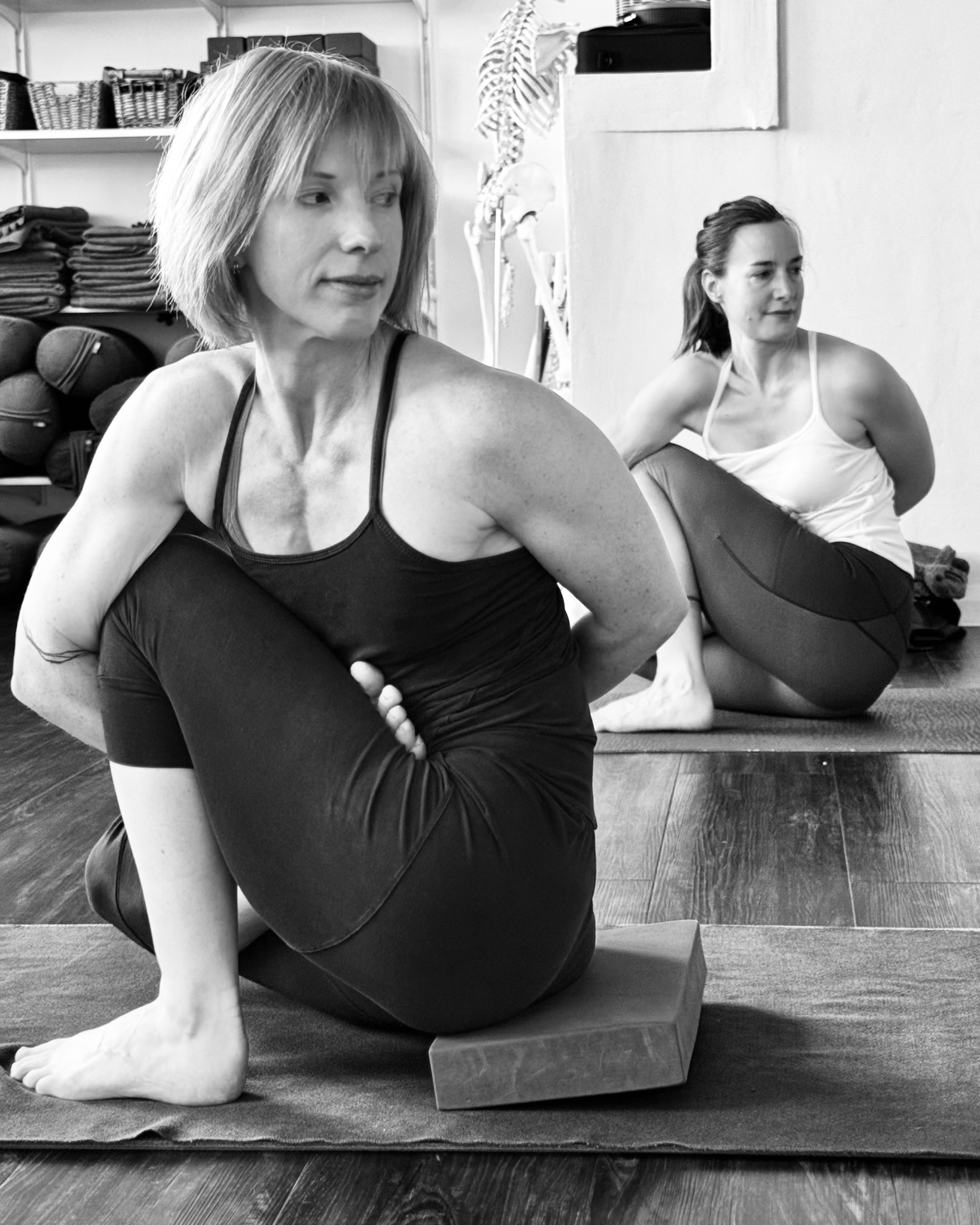 Two practitioners in a seated twist, in black and white
